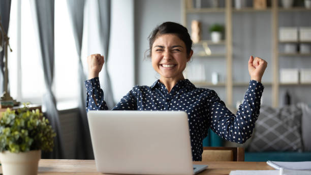 Euphoric young indian girl celebrate online victory triumph with laptop Euphoric young indian girl student winner celebrate victory triumph sit at home desk with laptop computer win online fortune feel excited get new job opportunity good exam result great news concept luck photos stock pictures, royalty-free photos & images