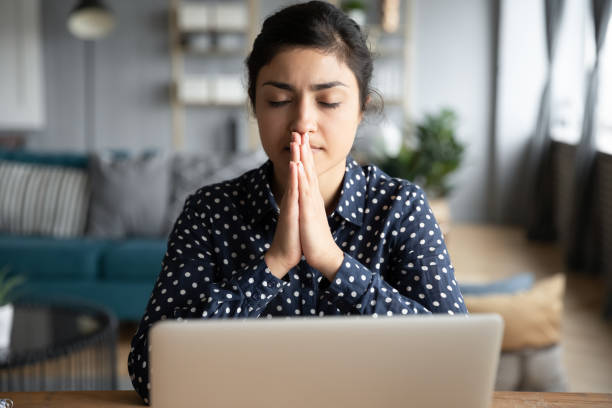 mujer india rezar hacer deseo sentarse en casa con portátil - female meditating human hand christianity fotografías e imágenes de stock