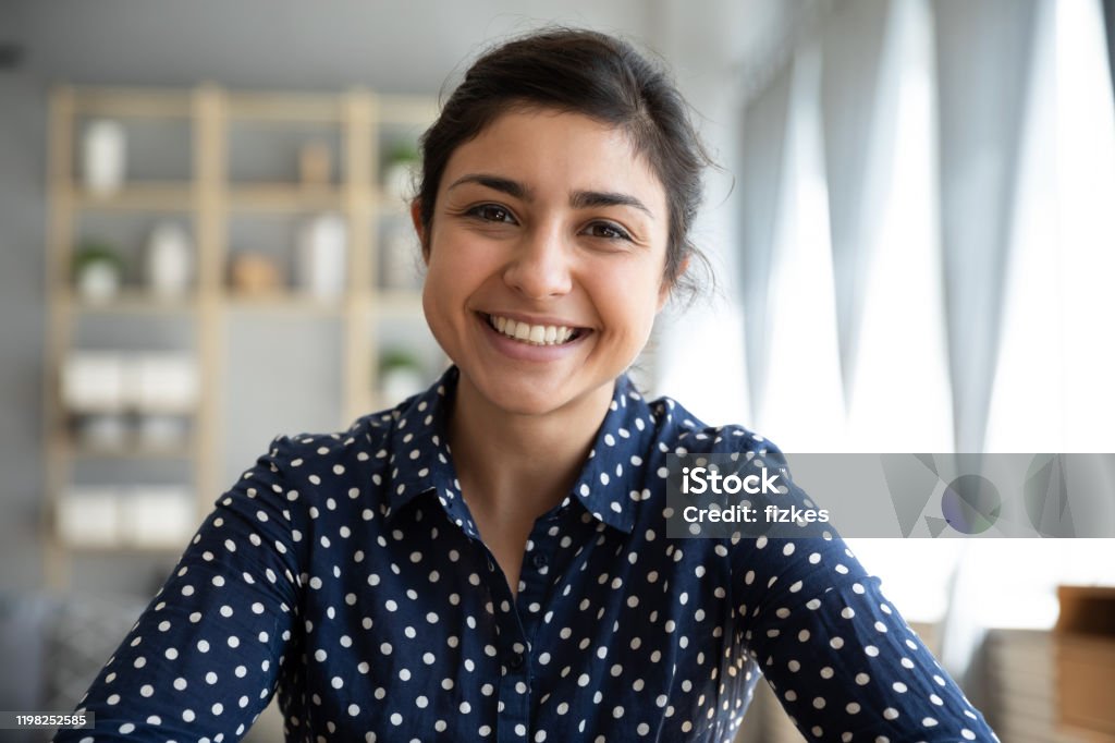 Happy indian woman look at webcam doing job interview videochat Happy young indian woman blogger applicant teacher sit at home office look at camera doing online job interview during video chat conference call record vlog teaching on webinar in app, webcam view Women Stock Photo