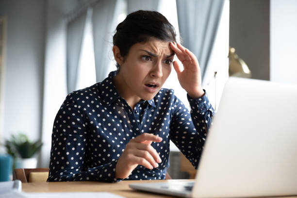 Shocked young indian girl look at laptop screen feel terrified Shocked afraid worried young indian girl look at laptop computer screen terrified read bullying social media message feel bad surprise stress panic about stuck computer problem concept at home office sad disbelief stock pictures, royalty-free photos & images