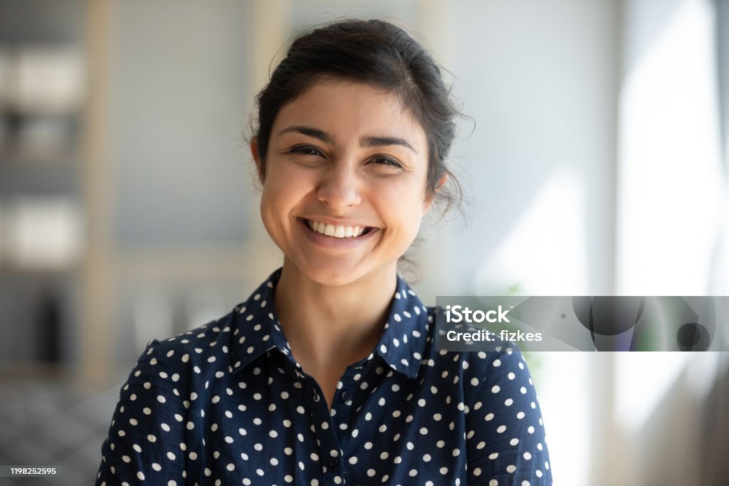 Chica india alegre de pie en la oficina en casa mirando a la cámara - Foto de stock de Mujeres libre de derechos