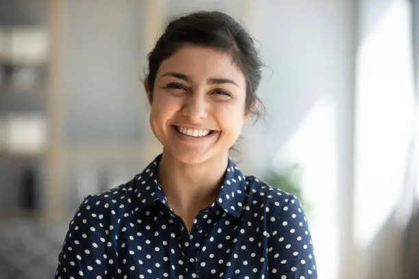 Photo of Cheerful indian girl standing at home office looking at camera