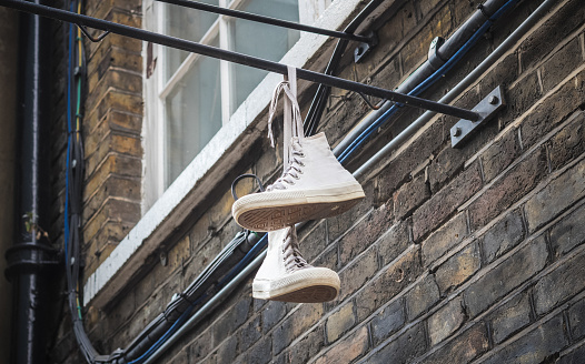 Shoes dangling outside a brick wall at Brick Lane market in London