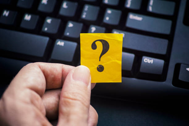 istock Man holding question mark in his hand against black computer keyboard 1198256757