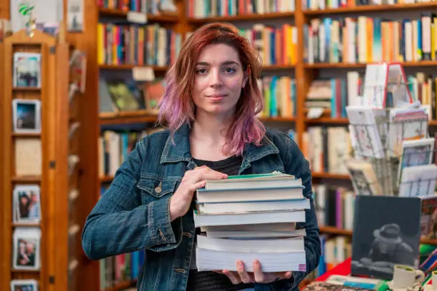 A woman holding a stack of books in the independent San Francisco bookstore where she works.