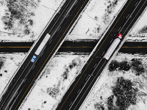 Aerial drone view of semi trucks travelling on a multi-lane highway.