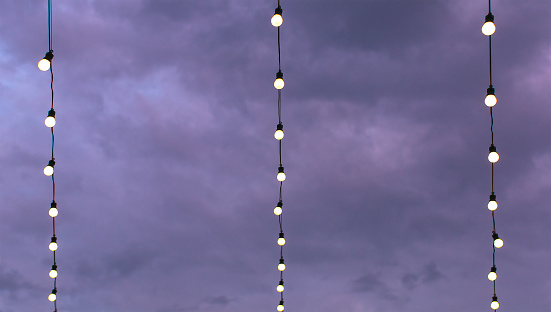 series of light bulbs on a wire with cloudy sky in the background