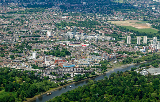 Aerial view of the London district of Brentford in Hounslow on a sunny summer day.  Brentford Football Club's Griffin Park stadium is in the middle with the River Thames to the bottom.