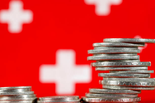 Swiss money coins and symbols of the Swiss flag Group of various Swiss money coins shown against the background of the Swiss flag symbols. swiss flag photos stock pictures, royalty-free photos & images