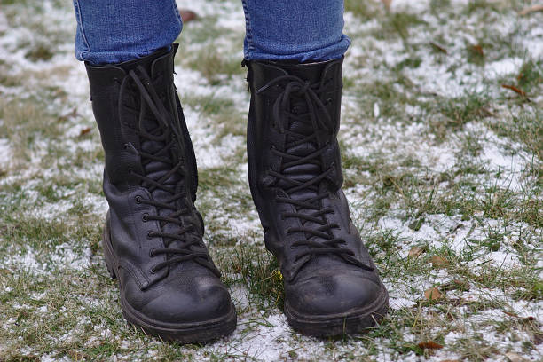 istock feet in high boots on the snow-dusted grass 1198265912