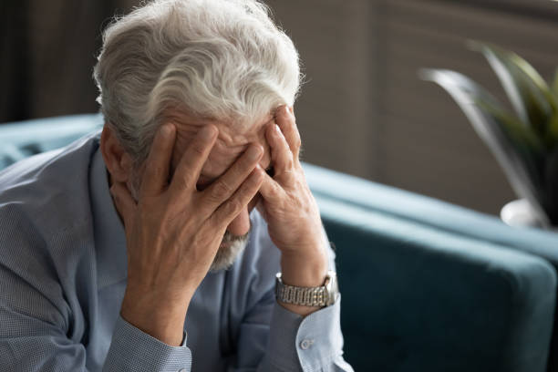 istock 50s man hides his face with hands looking desperate closeup 1198265961