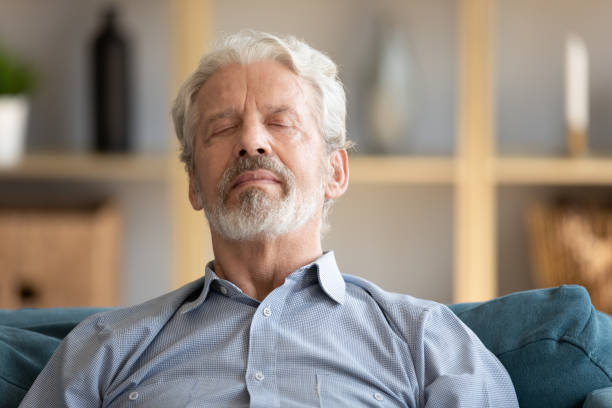 istock Elderly man closed eyes leaned on sofa having day nap 1198265962