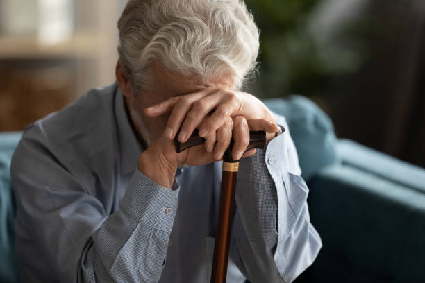 istock Sad elderly man covering his face with hand holding cane 1198265975