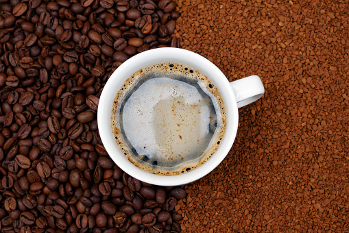 top view of filled cup of coffee on coffee beans and instant coffee background