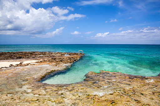 The rocky landscape with a ladder on Grand Cayman island Seven Mile Beach (Cayman Islands).