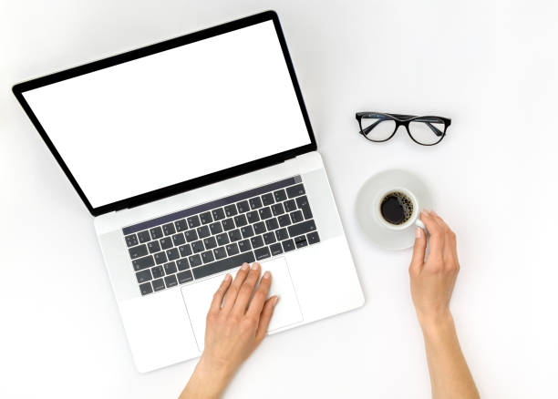 istock Home office workspace mockup. Laptop with blank screen, hands and accessories on white background. Flat lay. Top view 1198271473
