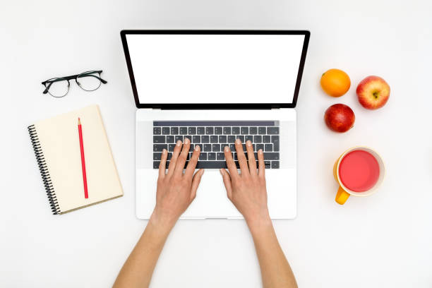 istock Home office workspace mockup. Laptop with blank screen, hands and accessories on white background. Flat lay. Top view 1198271474