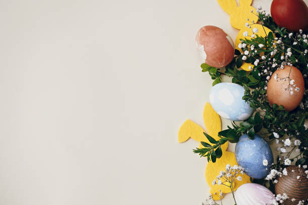 istock Stylish easter eggs, yellow bunny, spring flowers on yellow paper, space for text. Natural dyed easter eggs and rabbit decoration. Happy Easter 1198272777