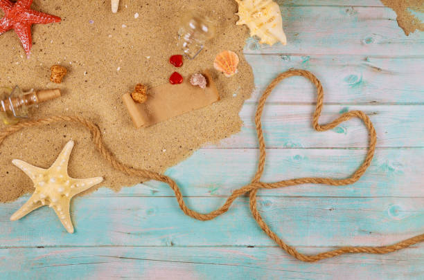 istock Valentines day symbol heart from nautical rope on ocean shore with shells and starfish. Papyrus from the glass bottle. 1198276802