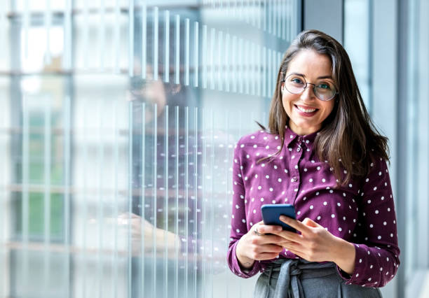 istock Smiling woman with a phone in office 1198277128