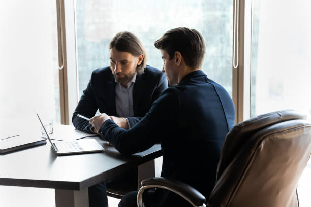 istock Concentrated businessmen discuss ideas cooperating at laptop 1198278186