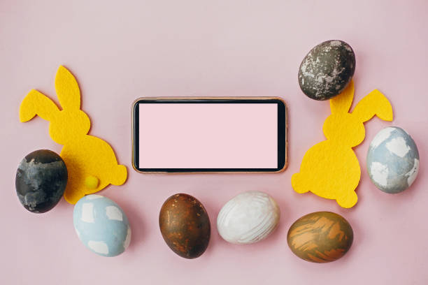 istock Phone with blank screen, stylish easter eggs, yellow bunnies on pink paper flat lay, space for text.  Happy Easter. Greeting card template. Modern natural dyed blue and marble easter eggs 1198278395