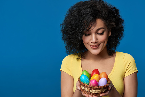 Happy woman holding a basket with colorful Easter eggs