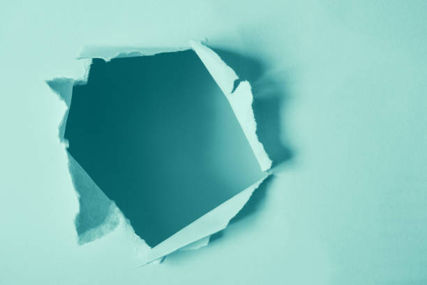 Round damaged hole in paper mint color with copy space. Torn ripped paper sheet with selective focus. Template for poster, banner stock photo