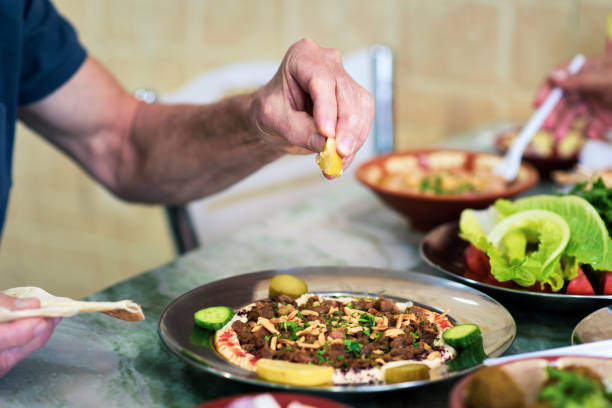 Person squeezing lemon on hummus with meat and Arabic food closeup