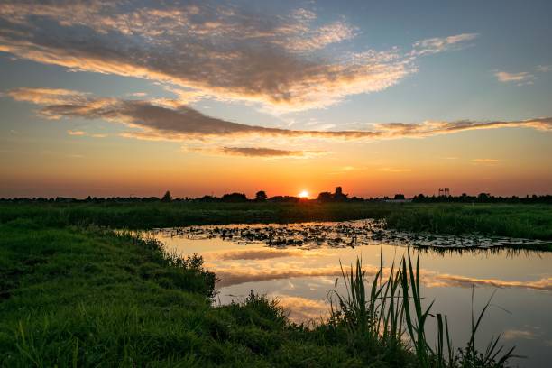Sun goes down over the polder landscape in Holland Sunset over the dutch countryside near Gouda. Beautiful colors and reflections in the water. gouda south holland stock pictures, royalty-free photos & images