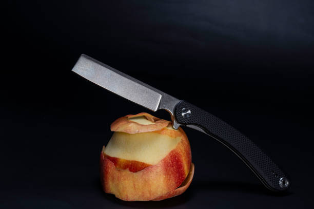 Knife and apple. A knife lying on an apple. A peeled apple. Apple on a black background.