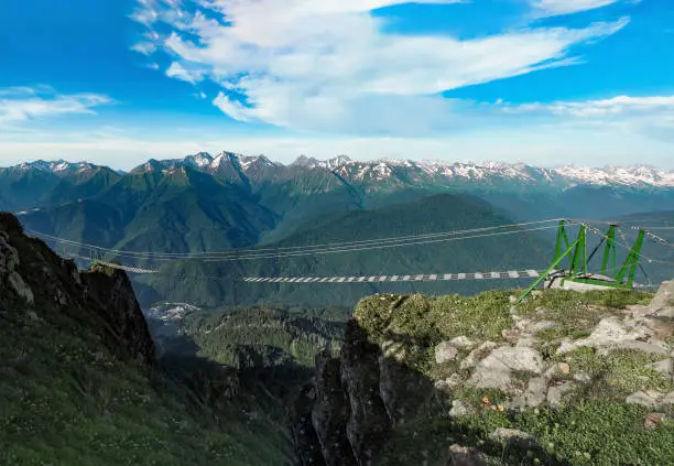 Panoramic view of hanging suspension bridge at mountains and sunny blue sky background