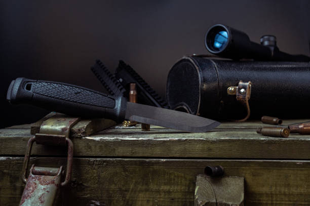 istock Knife and scope. A large knife and a hunting sight on a war box .. 1198296135