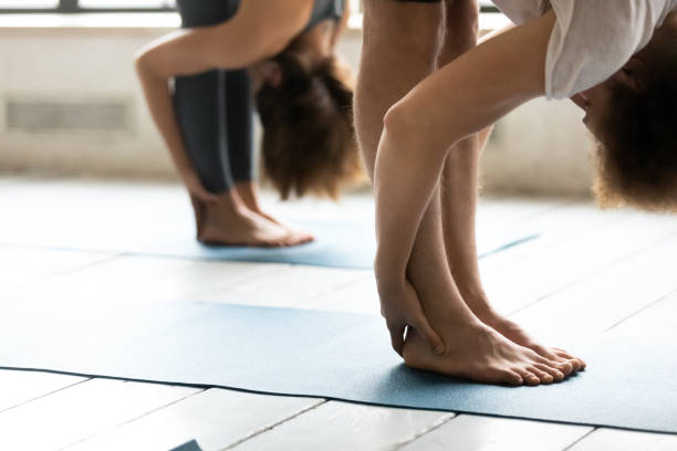 istock Close up people stretching in uttanasana pose, practicing yoga 1198296919