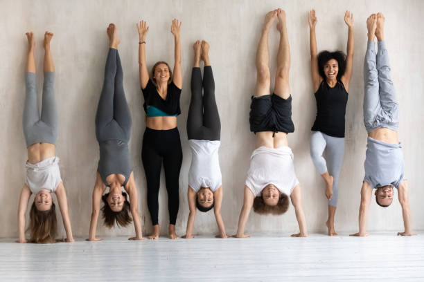 personnes diverses heureuses faisant le handstand, portrait de personnel de centre de forme physique - équilibre sur les mains photos et images de collection