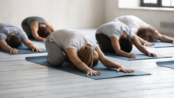 diversas personas haciendo ejercicio infantil en la clase grupal, practicando yoga - centro de yoga fotografías e imágenes de stock