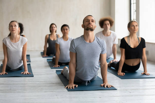 zróżnicowani ludzie robią ćwiczenia kobry na lekcji grupowej, ćwiczą jogę - yoga class instructor yoga exercising zdjęcia i obrazy z banku zdjęć