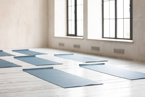 alfombrillas de yoga sin enrollar en suelo de madera en un gimnasio vacío - pilates health club gym exercising fotografías e imágenes de stock