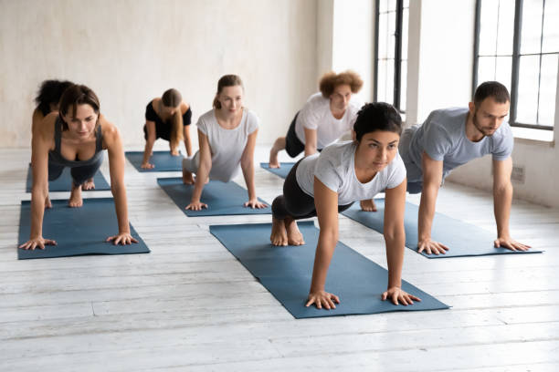 vielfältige menschen, die plank-übungen im gruppenunterricht machen, yoga praktizieren - core strength stock-fotos und bilder