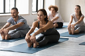 Woman practicing yoga at group lesson, Seated forward bend exercise