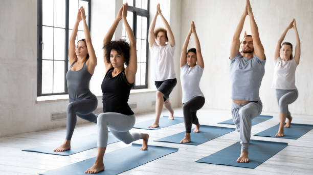 istock Diverse people doing Warrior one exercise at group yoga lesson 1198298354