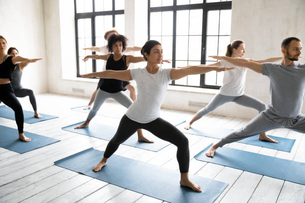 istock Diverse young people doing Virabhadrasan exercise, practicing yoga 1198298379
