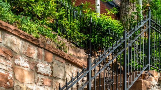 Pano frame Outdoor staircase with stone steps and black metal railing against a fence Pano frame Outdoor staircase with stone steps and black metal railing against a fence. Close up of a sunlit stairway with house and plants at the top. baluster stock pictures, royalty-free photos & images