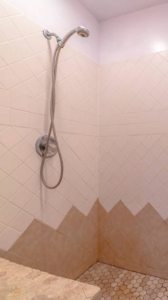 istock Vertical Bathroom interior with shower installed on the wall with white and brown tiles 1198308302