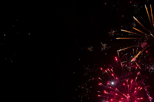 Red and orange fireworks placed in the corner of composition with big black copy space