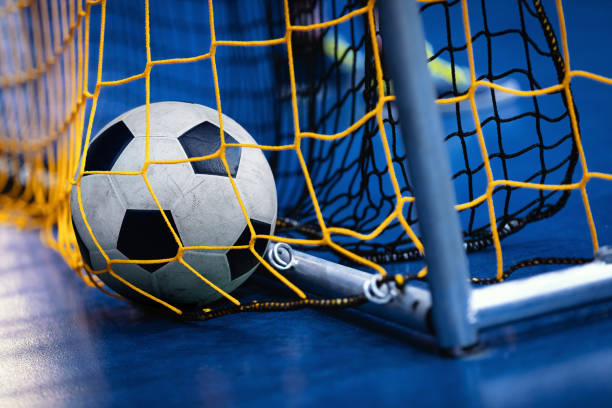крытый футбол футзал мяч по воротам с чистой и синий фон. крытый футбол фон - soccer goal net winning стоковые фото и изображения