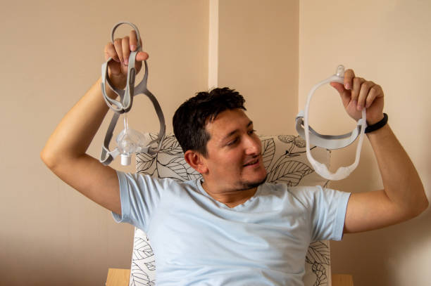 Man looking at under the nose nasal CPAP mask with happy face stock photo