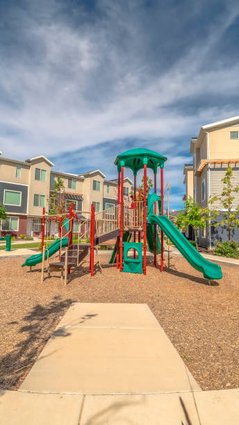 istock Vertical frame Pathway around childrens playground against townhomes and cloudy blue sky 1198315129