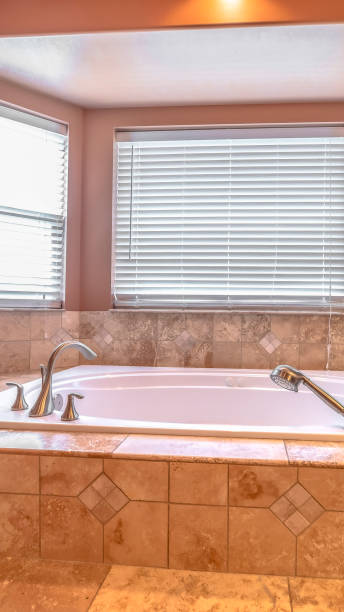 istock Vertical frame Bathroom interior with close up of bay windows and elevated built in bathtub 1198317813