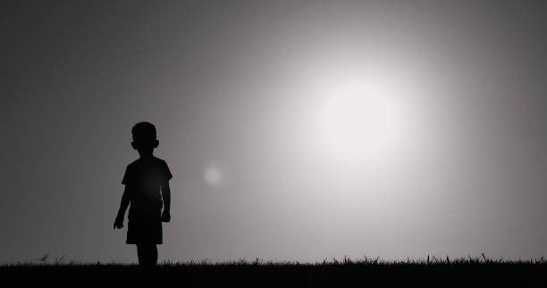 silhouette di un bambino piccolo che cammina in un campo. - sadness child little boys loneliness foto e immagini stock